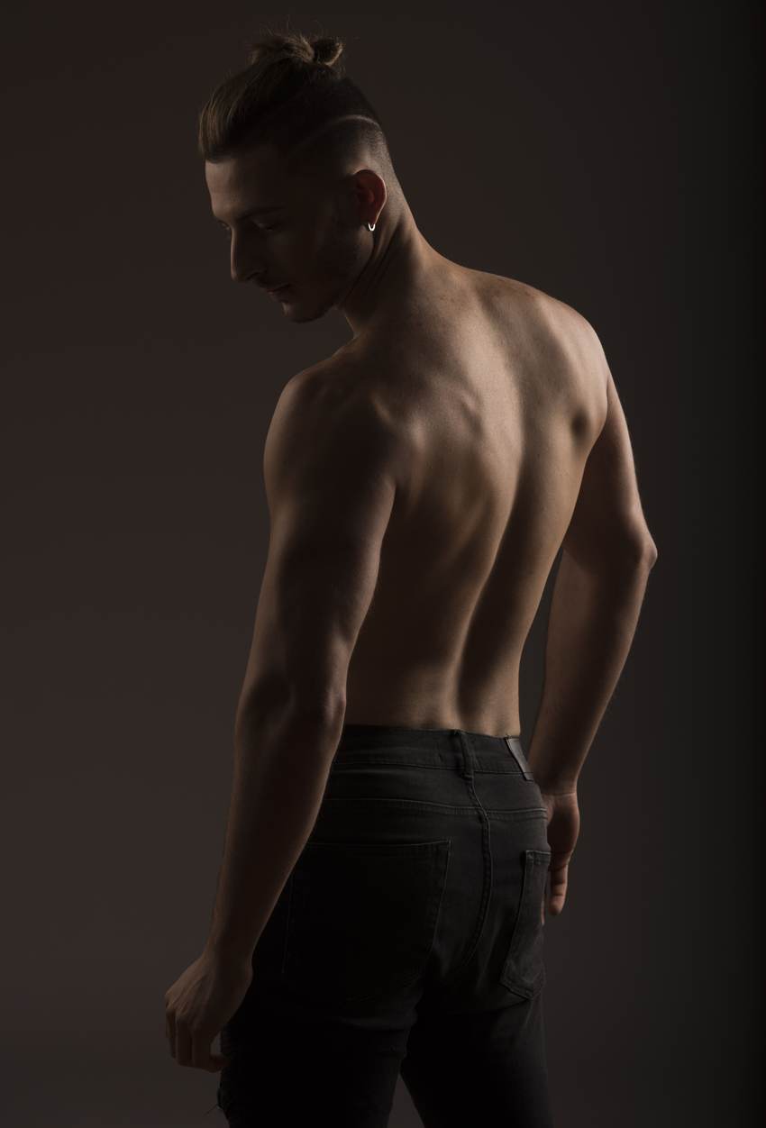 Studio portrait from behind, head lowered, low warm light