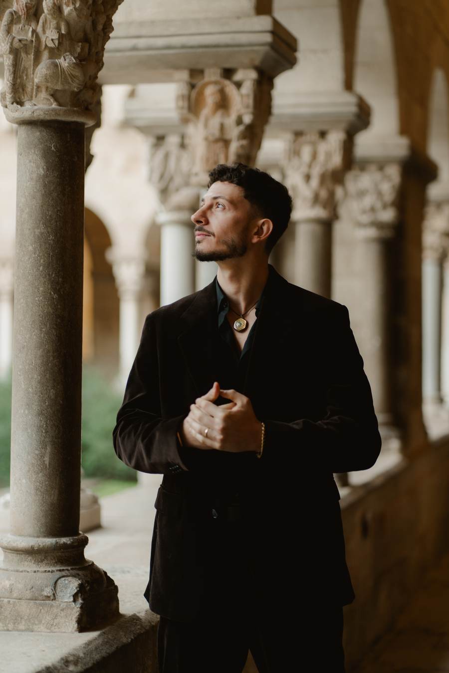 Michael standing in a stone cloister, looking upward into the light