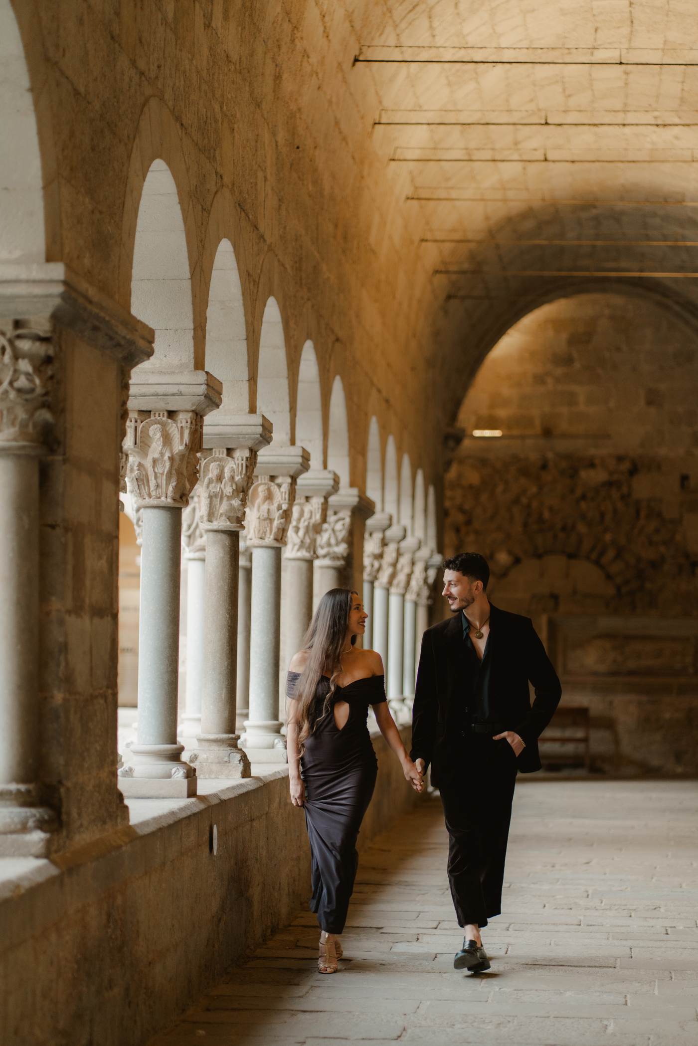 Michael walking hand in hand with a partner through a stone cloister