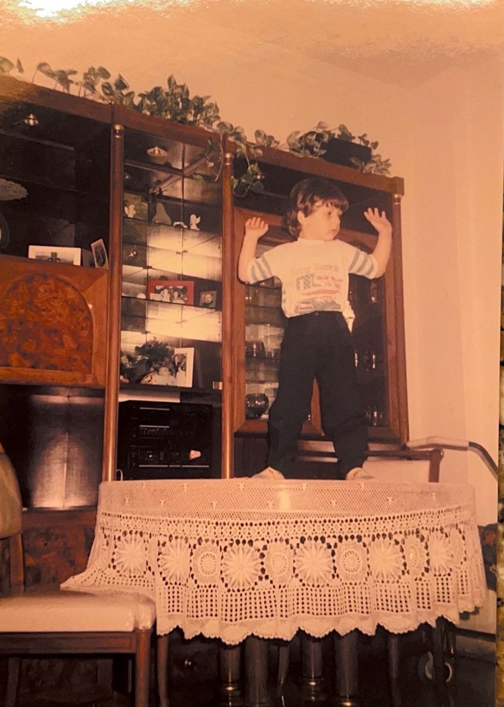 Michael as a small boy, standing on a table with his arms in the air